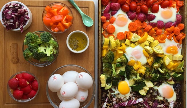 A sheet pan with baked radicchio, zucchini, broccoli, squash, peppers, and sunny side up eggs.